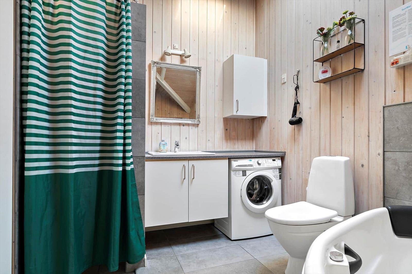 Bathroom with shower, washing machine, and toilet.