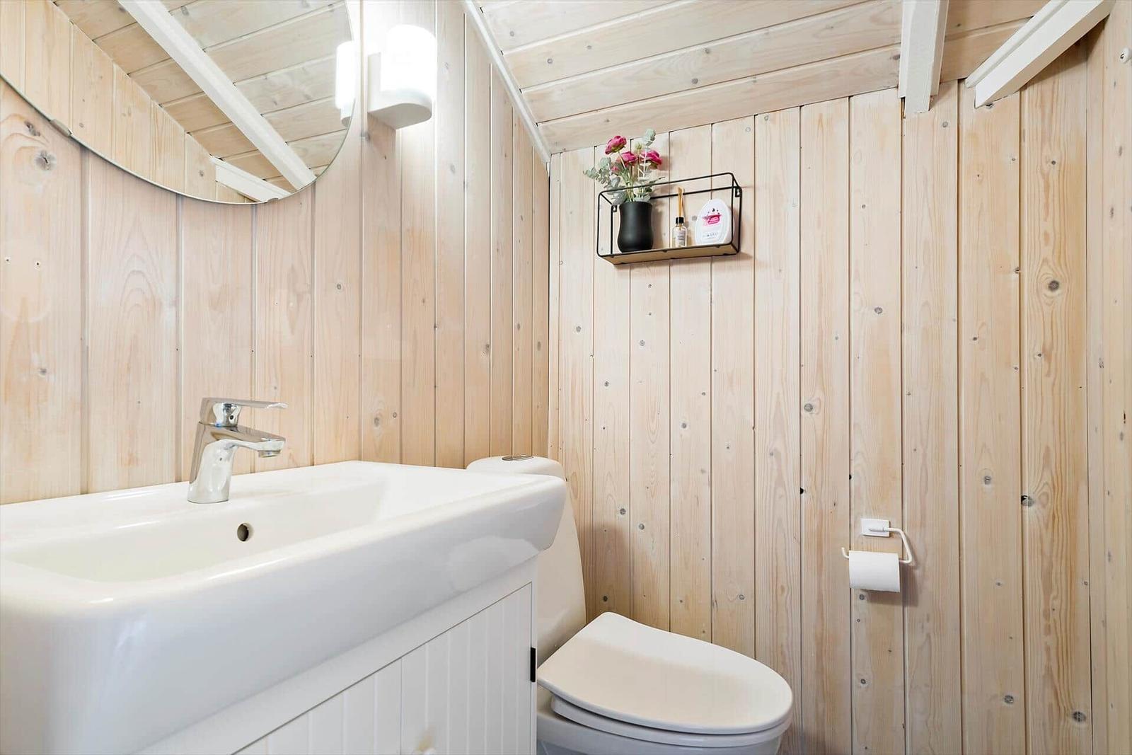 Bathroom with wooden walls, sink, and toilet