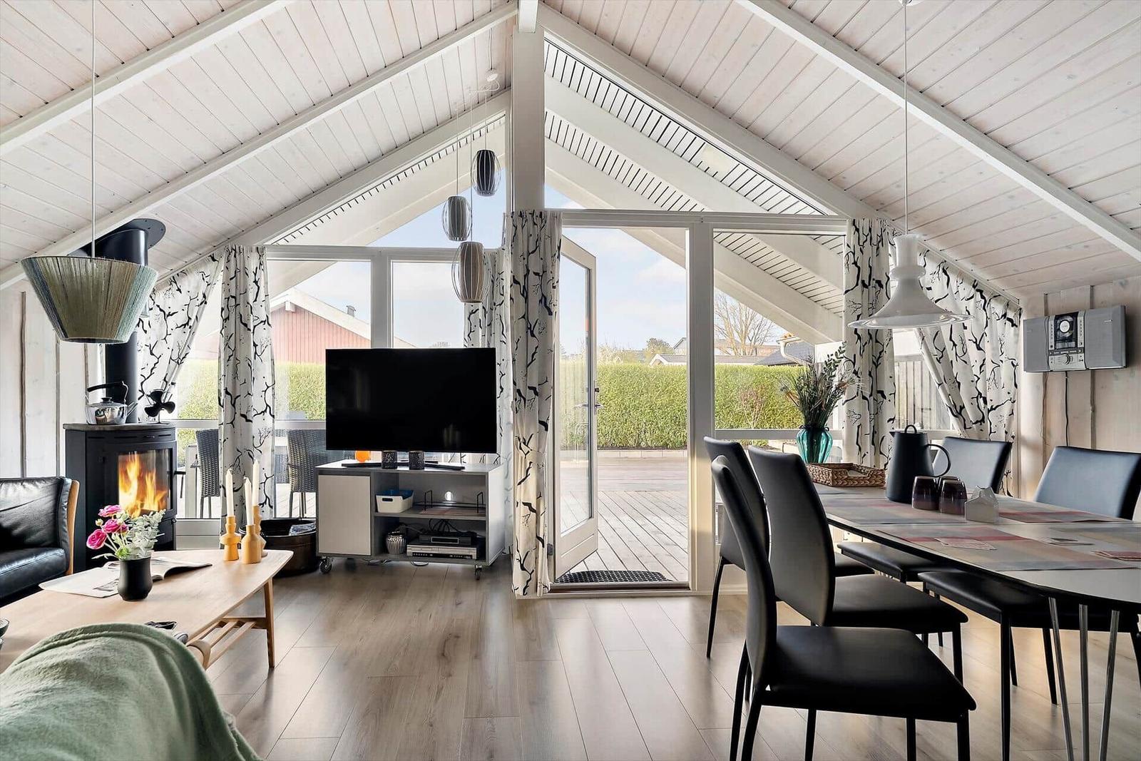 Living and dining area with fireplace, TV, and terrace.