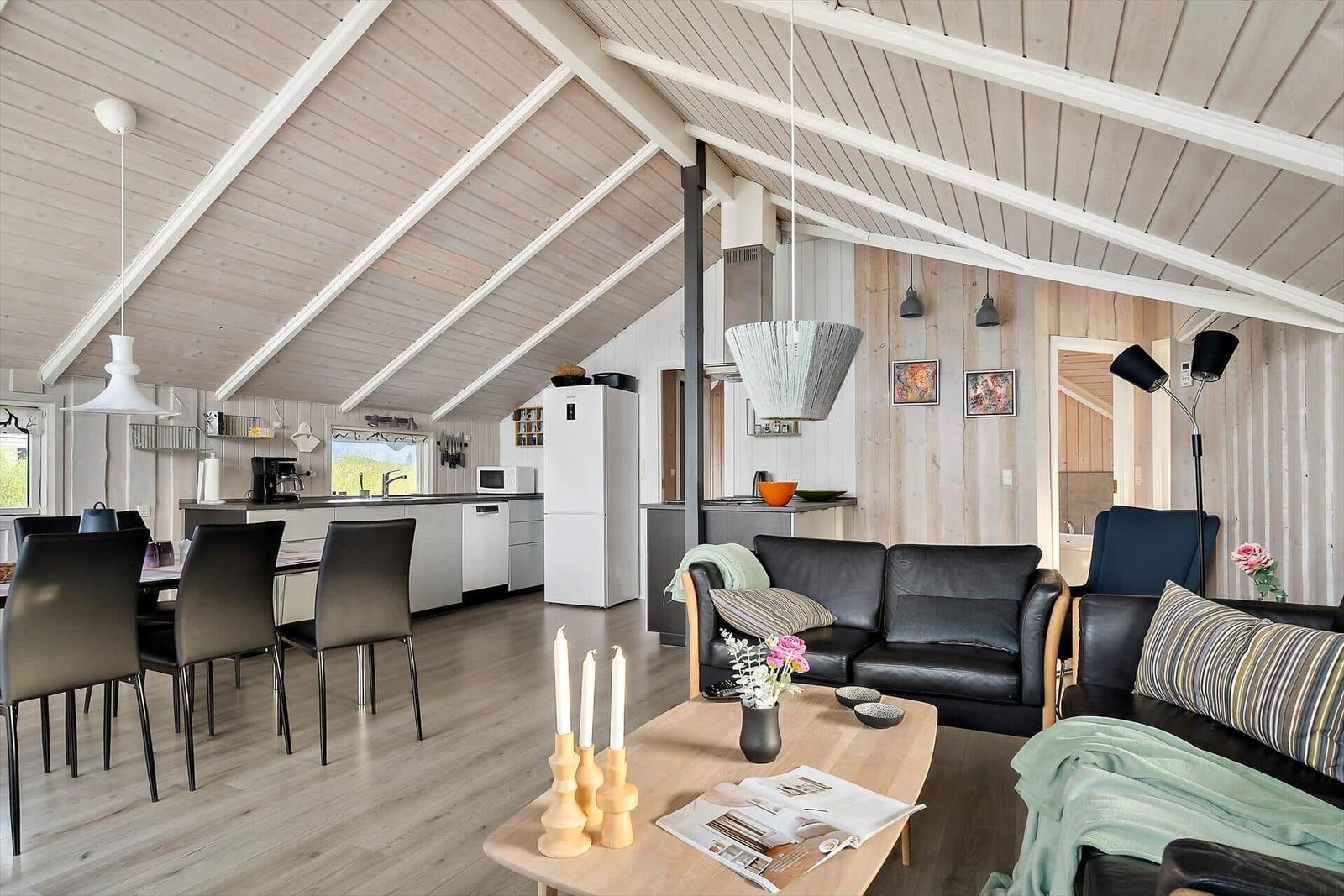 Living area with dining and kitchen under wooden ceiling.