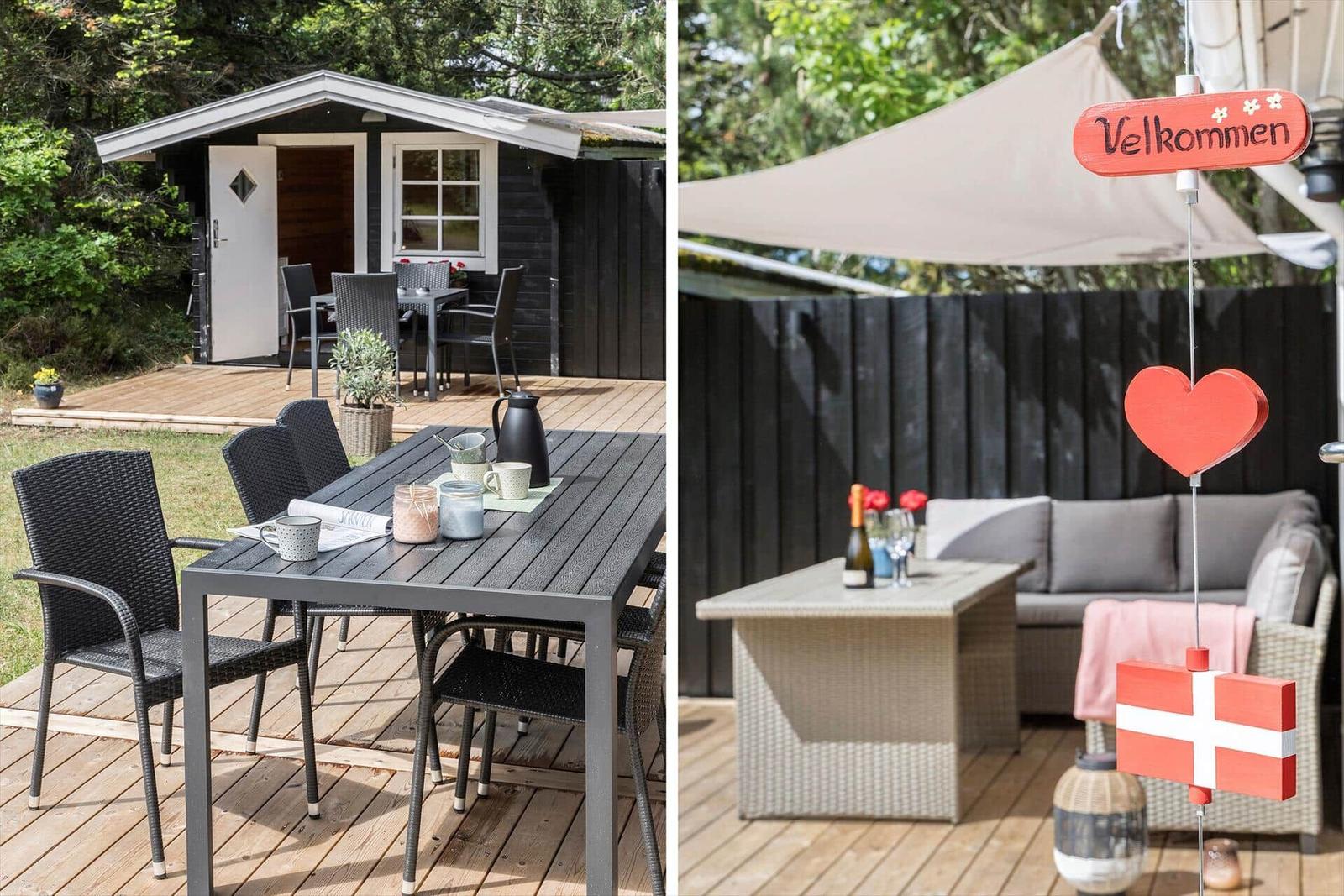 Terrasse mit Tisch, Stühlen und Sitzgruppe unter Sonnensegel. Willkommensschild und dänische Flagge.