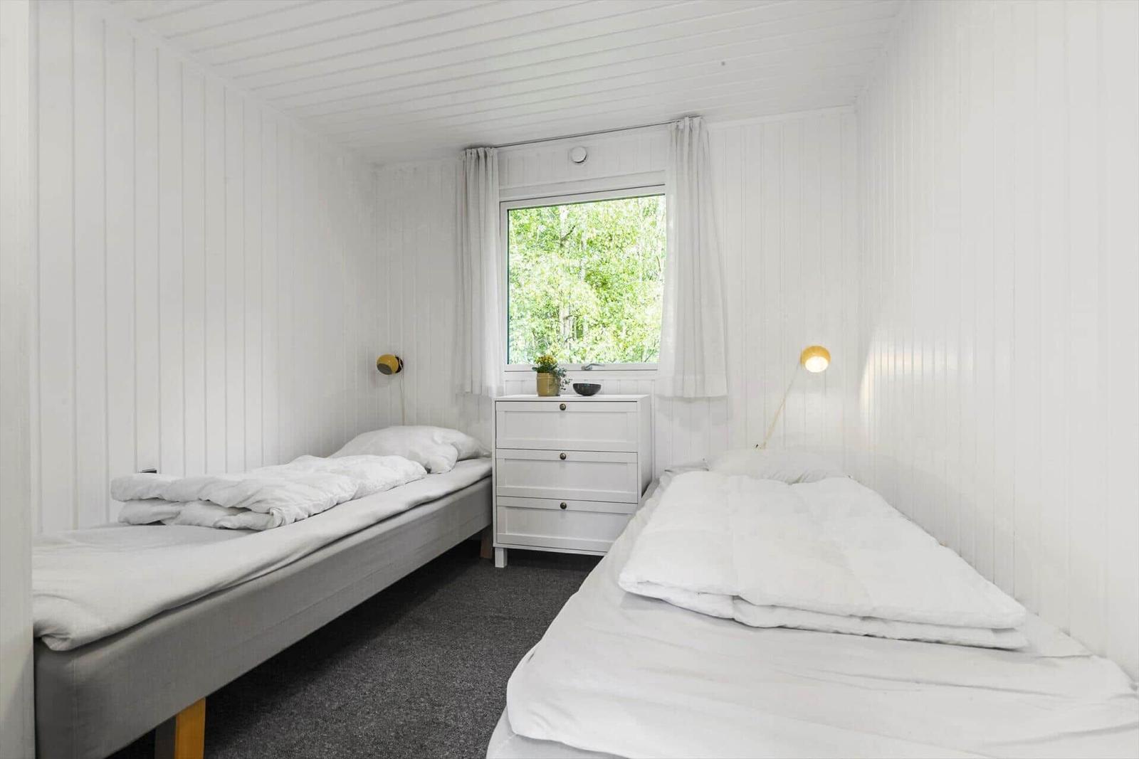 Zwei Betten, Schrank und Fenster mit Blick auf Grün.