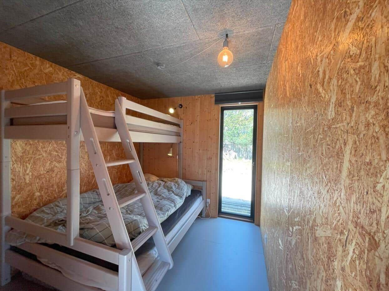 Zimmer mit Doppelstockbett, Holzwand und Fenster zum Ausblick.