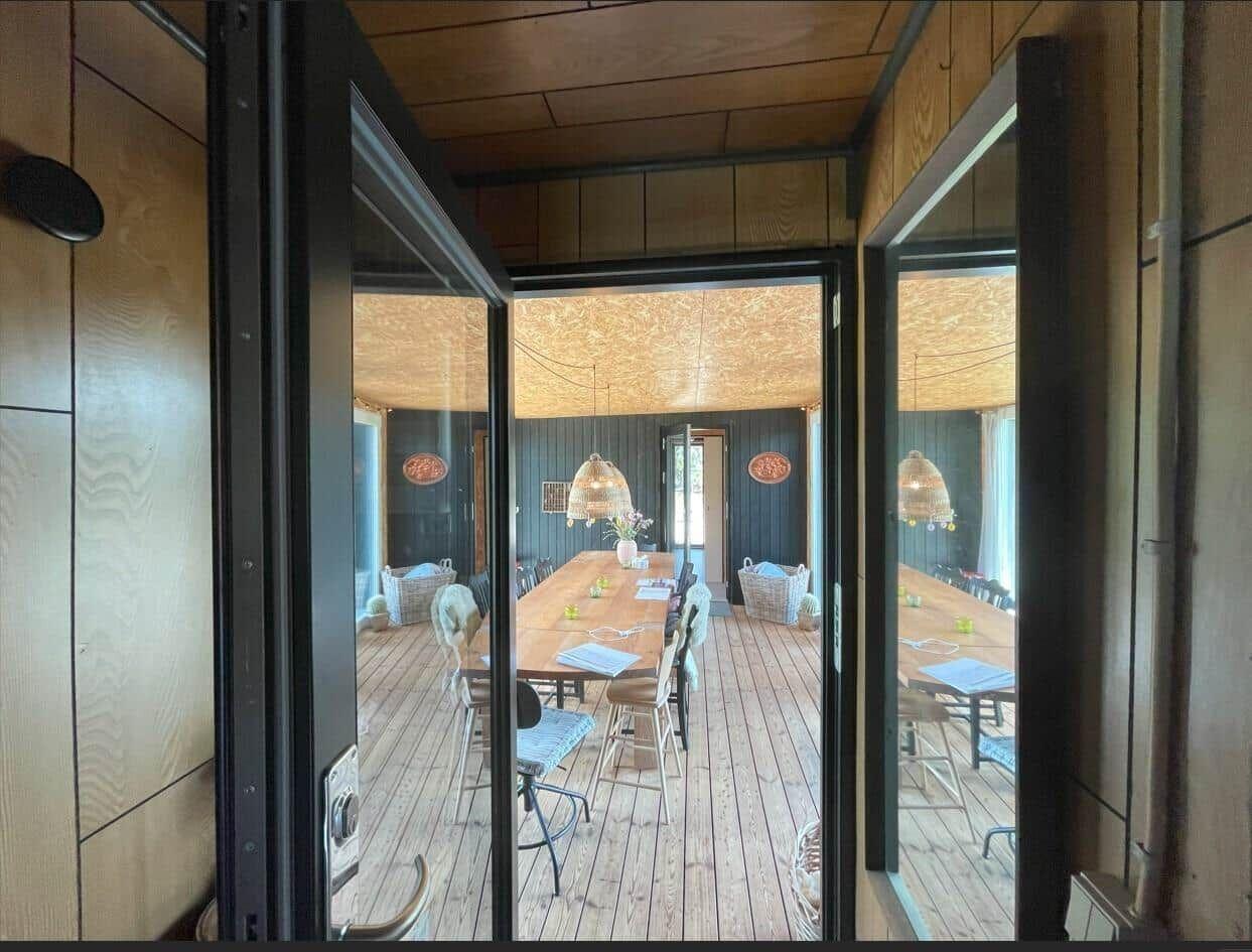 Durchgehende Glasfront führt in Esszimmer mit Holztisch und Stühlen.
