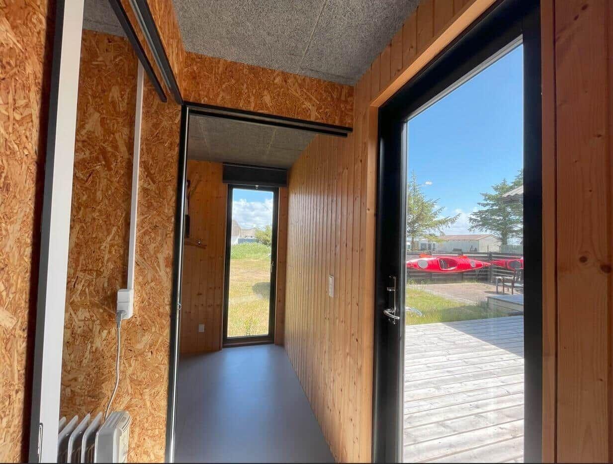 Flur mit Holzwänden, Glastür zum Balkon und Blick auf Ruderboote.