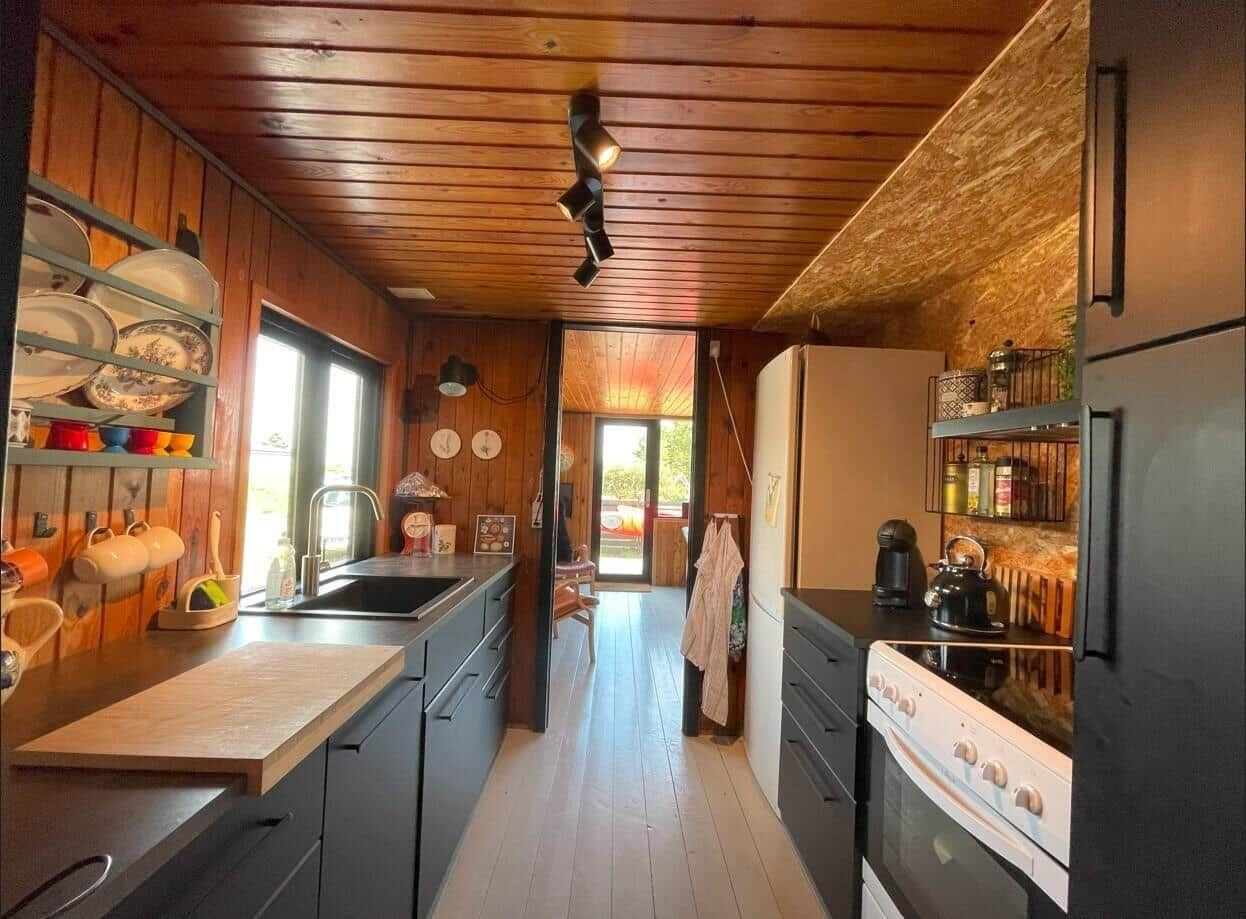 Küche mit Holzwänden, Arbeitsplatte und Küchengeräten.