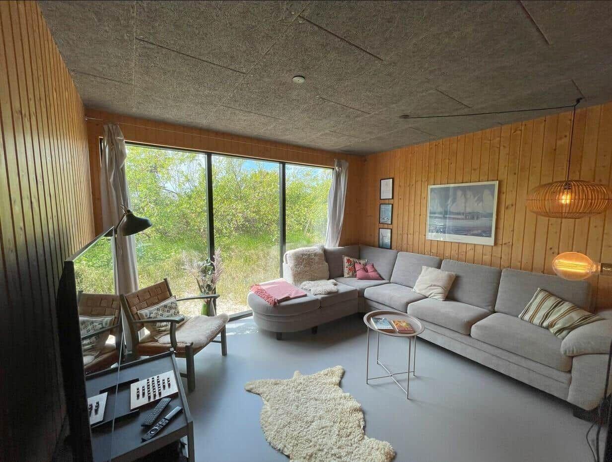Wohnzimmer mit Sofa, Sessel und großem Fenster zur Aussicht.