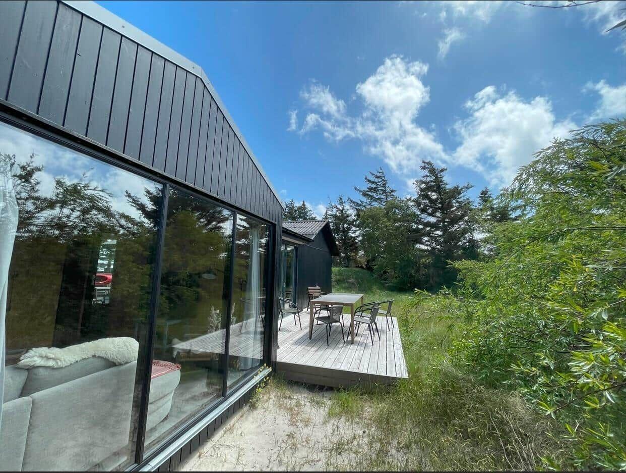 Moderne Unterkunft mit Terrasse, Tisch und Stühlen im Grünen.