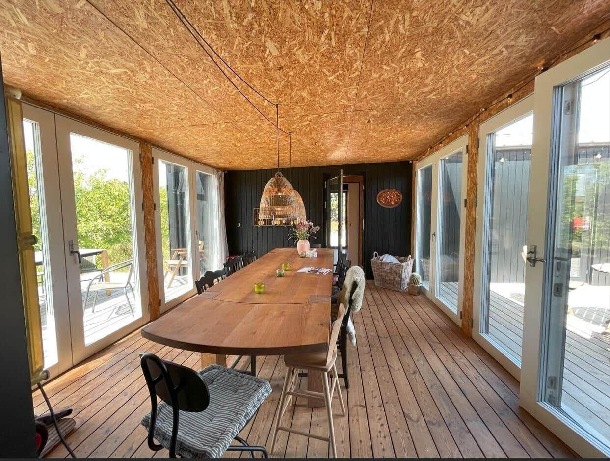 Esszimmer mit Holztisch, Stühlen und Glasfronten zur Terrasse.