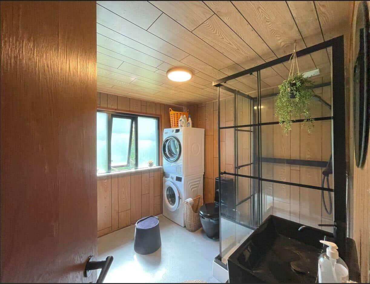 Badezimmer mit Dusche, Waschmaschine und Fenster mit Blick.