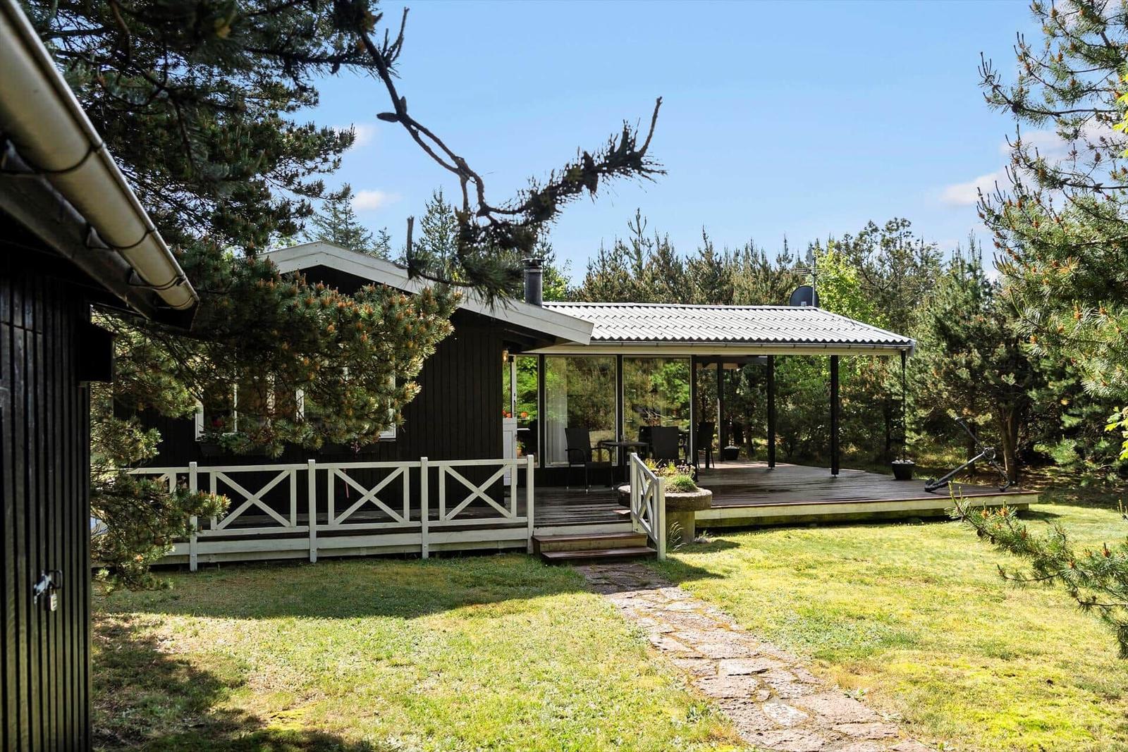 Haus mit Terrasse und Garten. Umgeben von Bäumen. Steinerne Wegführung.