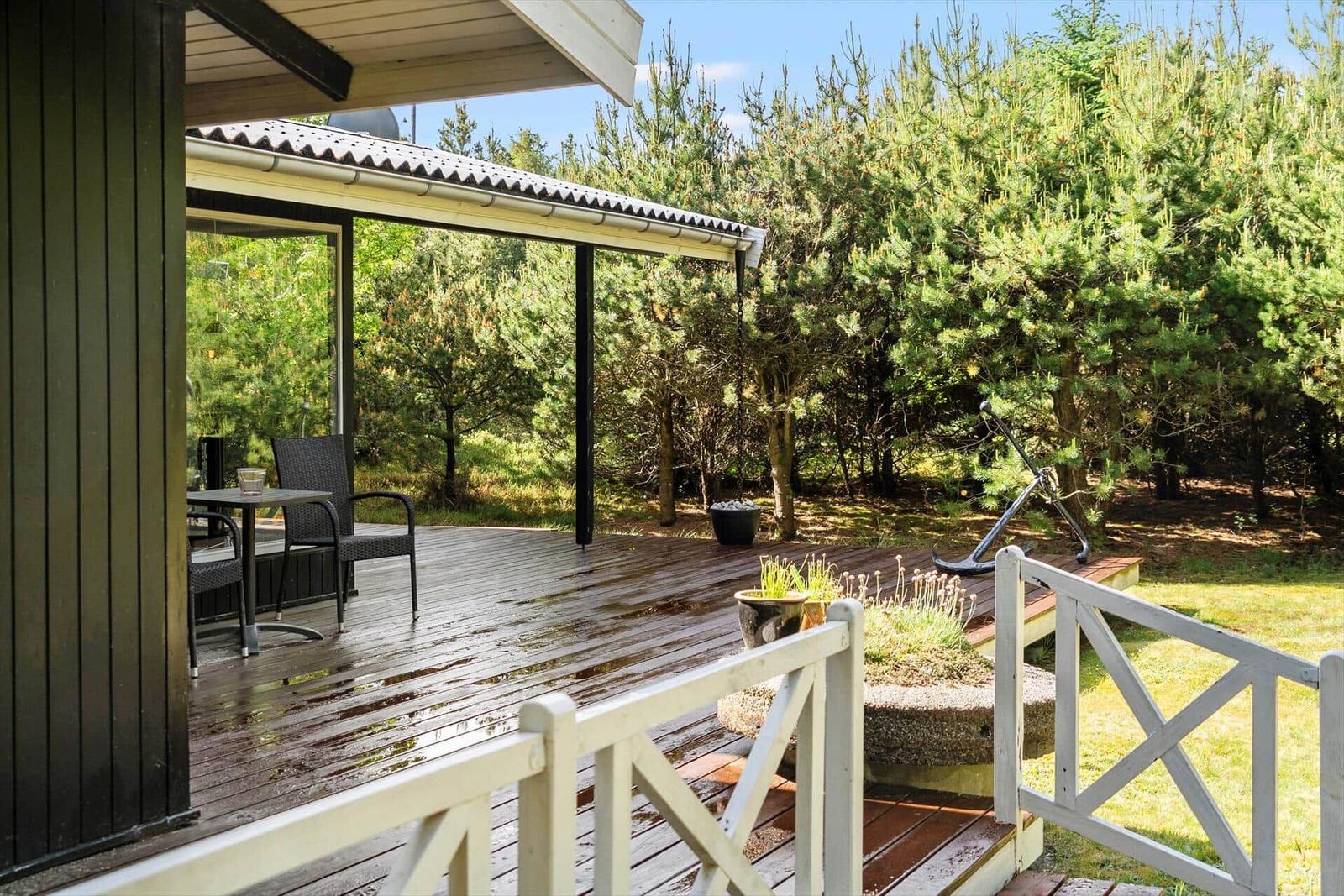 Terrasse mit Tisch, Stühlen und Blick in den Wald.