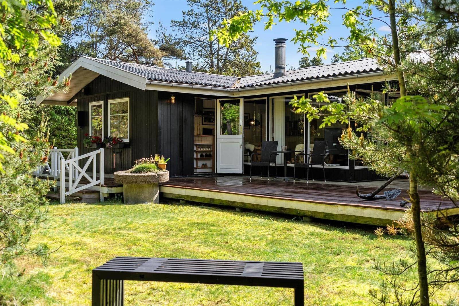 Holzhütte mit Terrasse, Garten und Blick in den Wald.