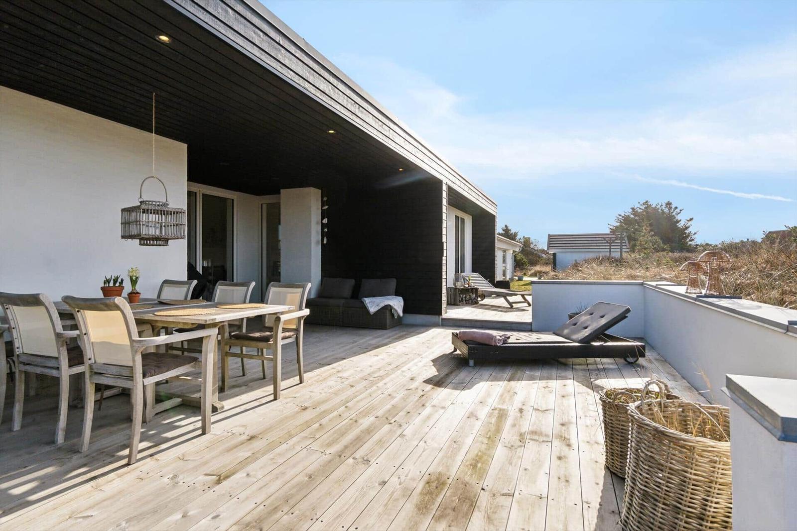 Deck with dining table, lounge chair, and garden furniture outdoors.