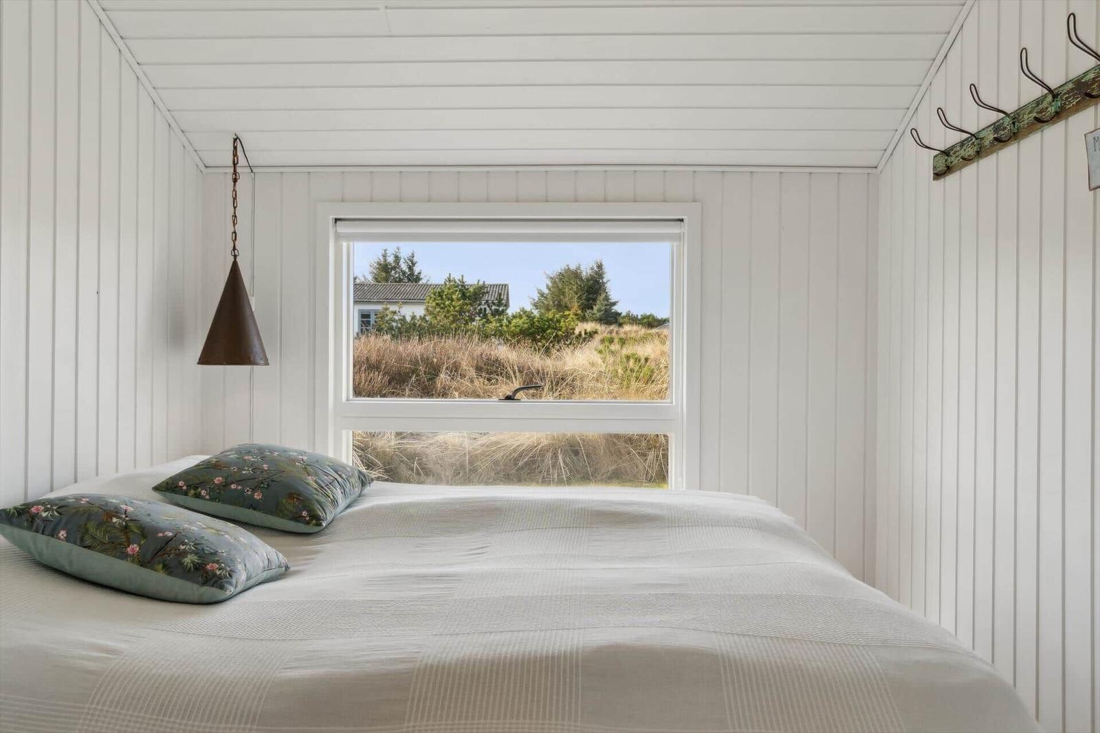 Bedroom with bed, window, and hook wall.