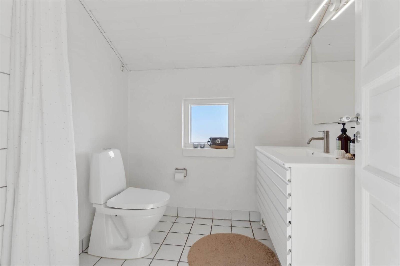 Bathroom with toilet, sink, and small window.