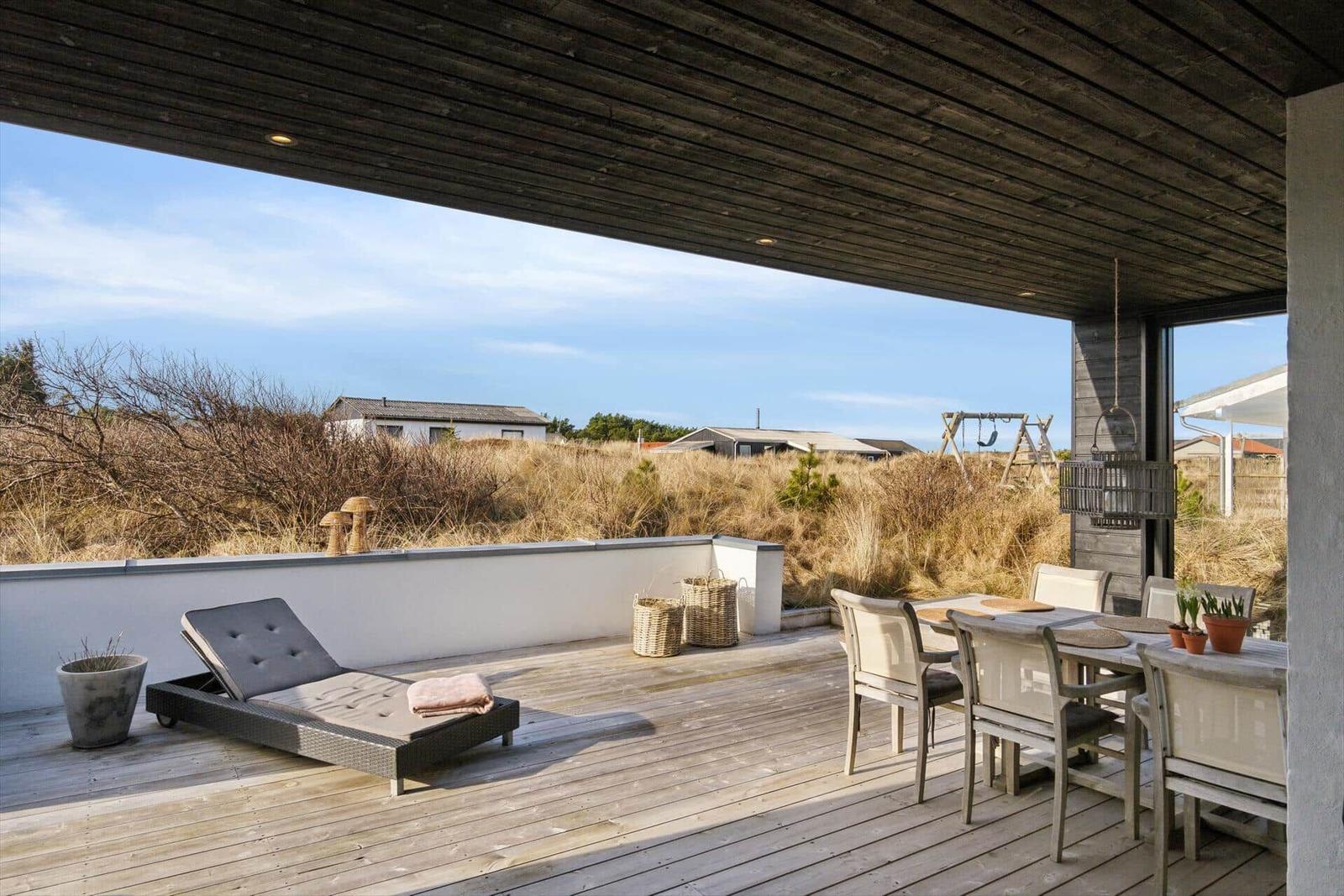 Deck with lounge, table and chairs. View of dunes and sky.