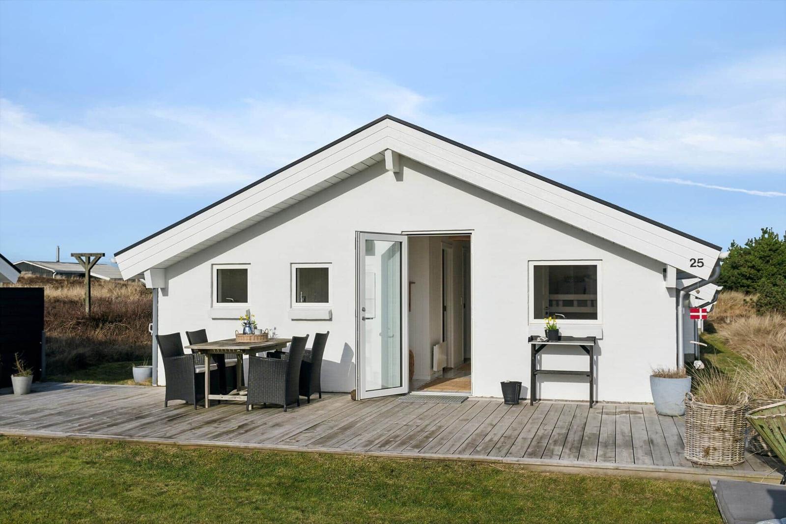 Modern white holiday home with terrace and garden table. House number 25. Danish flag attached.