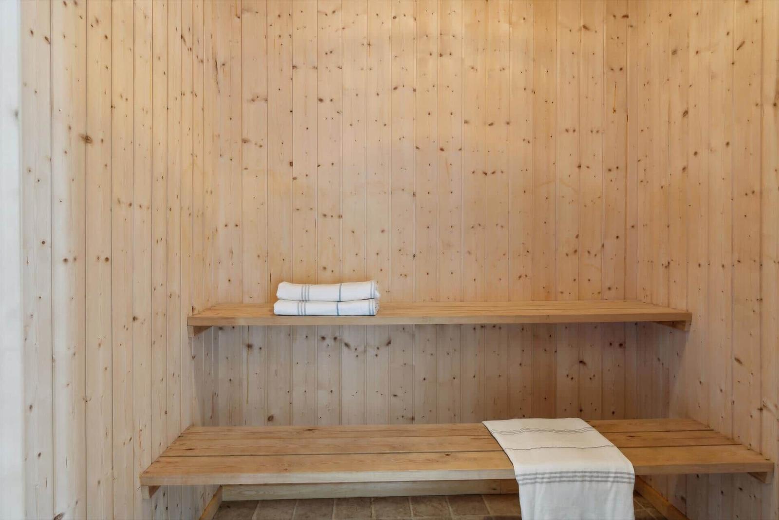 Sauna with wooden walls, bench, and towels.
