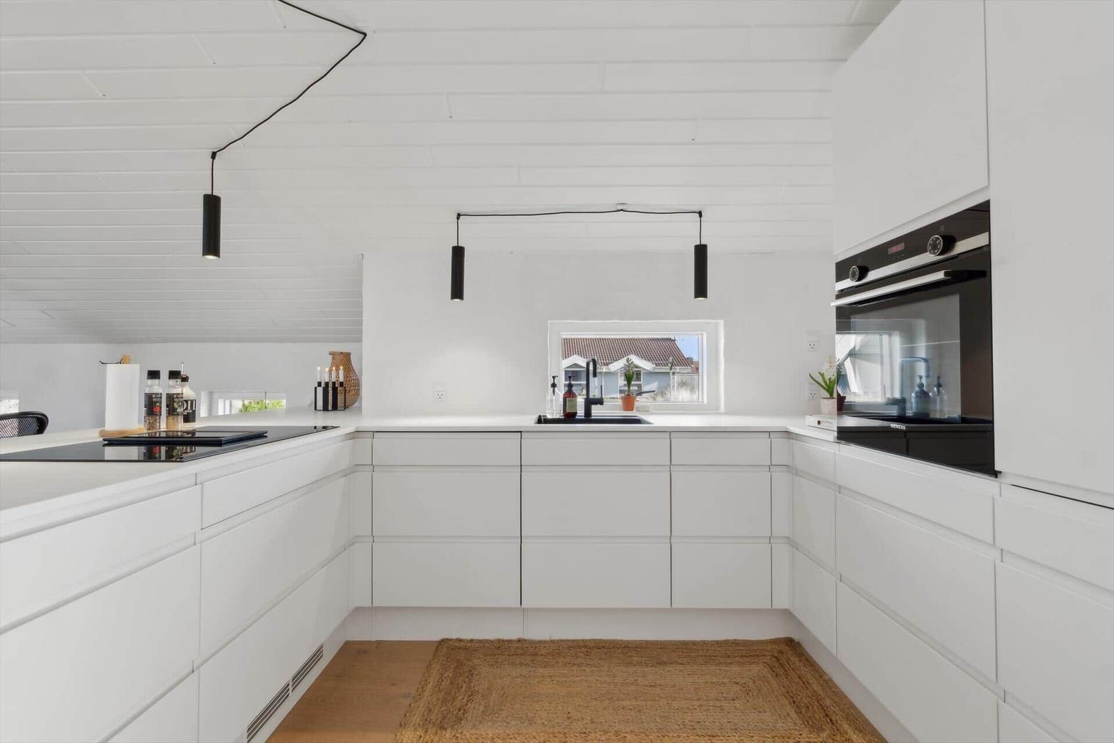 Modern kitchen with white cabinets and built-in oven.