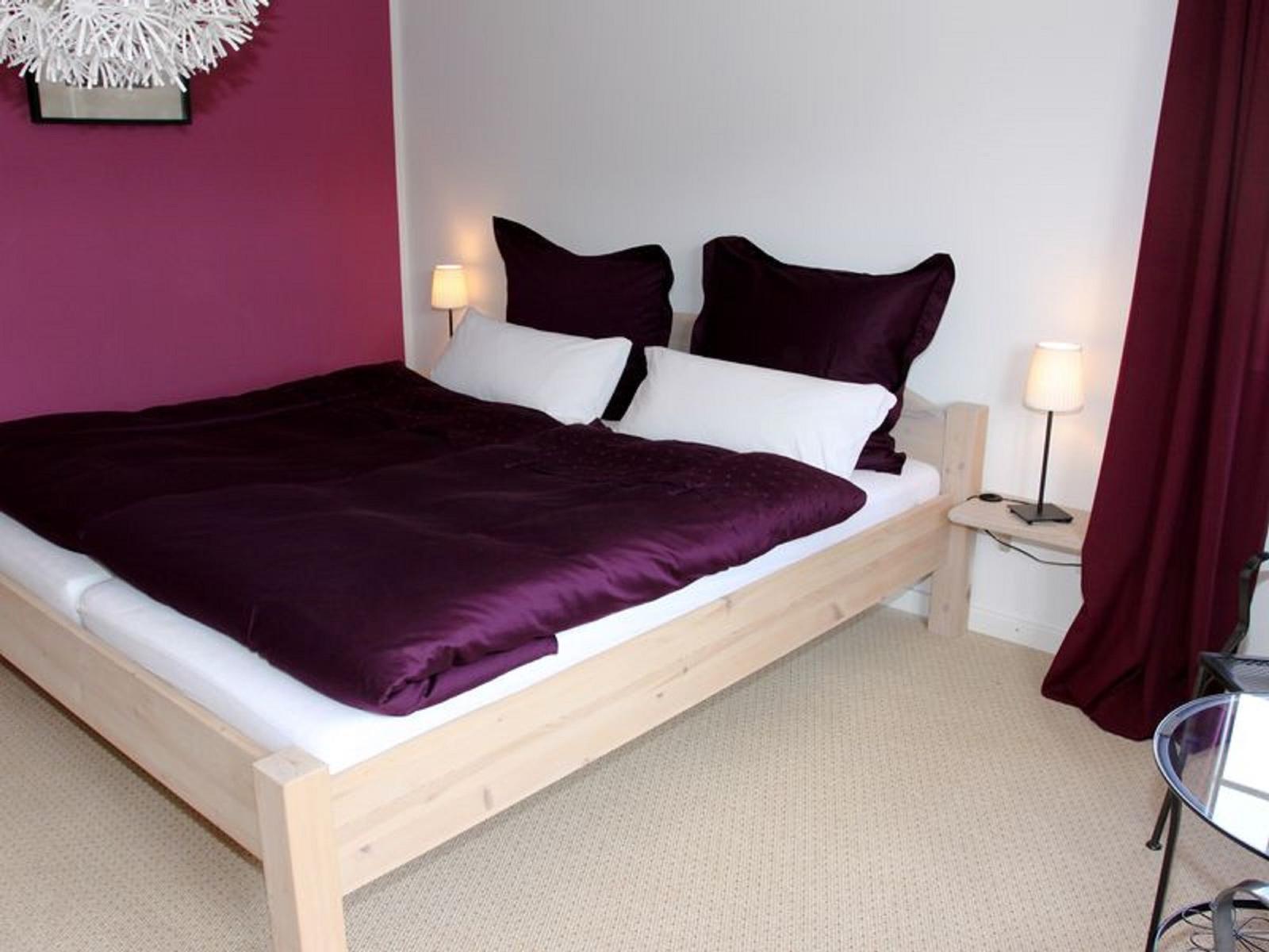 Ein Schlafzimmer mit Bett, Nachttisch und Vorhängen.