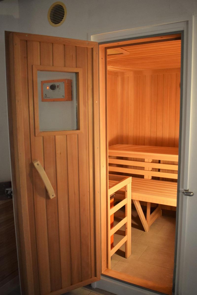 Sauna mit Holzbank und Tür mit Bedienfeld.