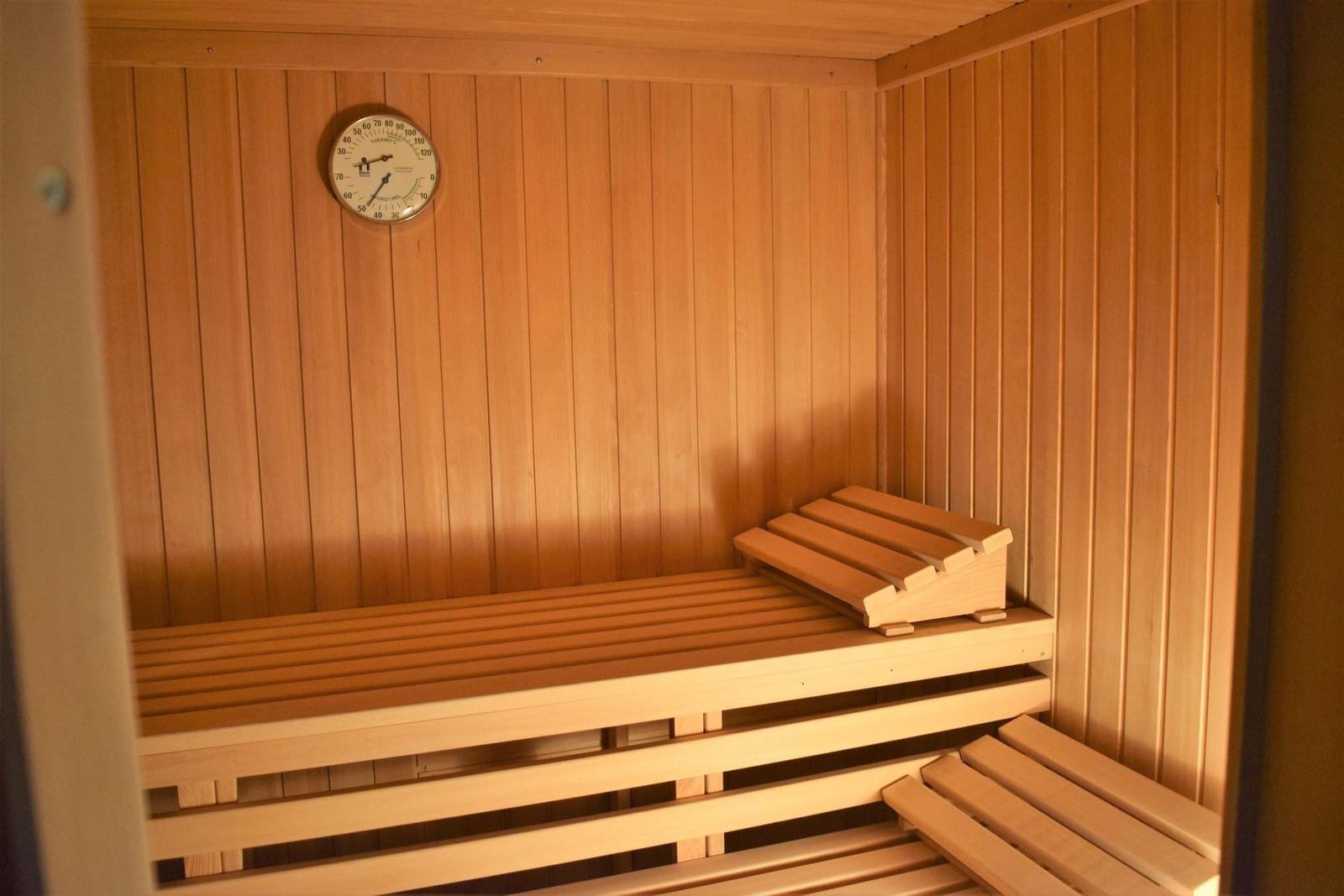 Sauna mit Holzbank und Temperaturuhr an der Wand.