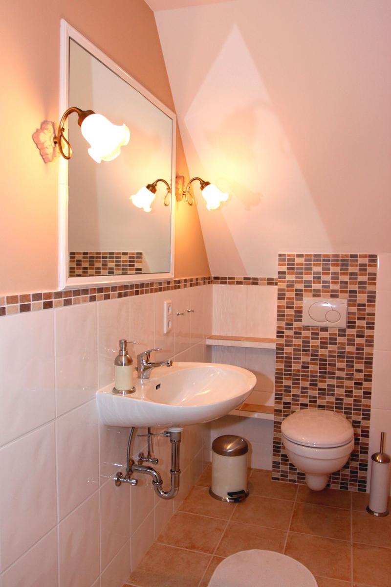 Badezimmer mit Waschbecken, Toilette und Spiegel mit Beleuchtung.