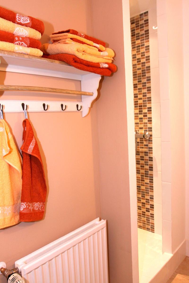 Bad mit Dusche, Handtüchern und Heizkörper