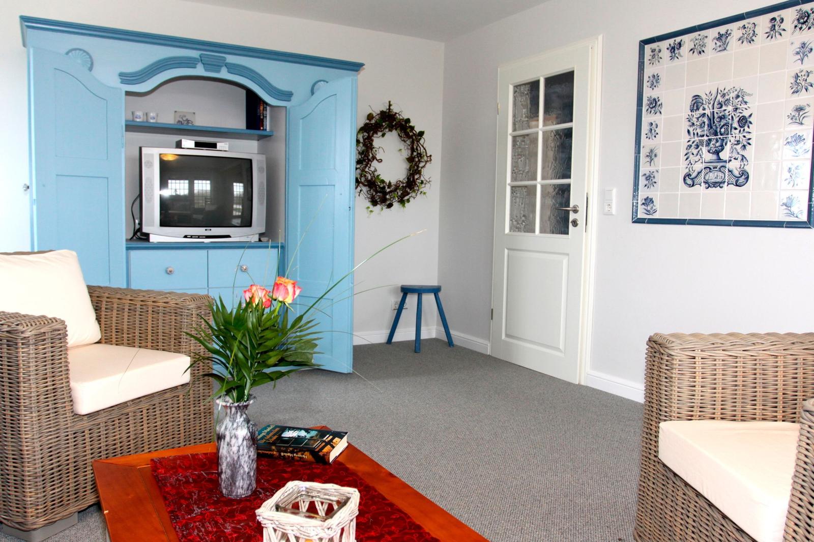 Wohnzimmer mit blauem Schrank, Wicker-Sofas und Kachelwand