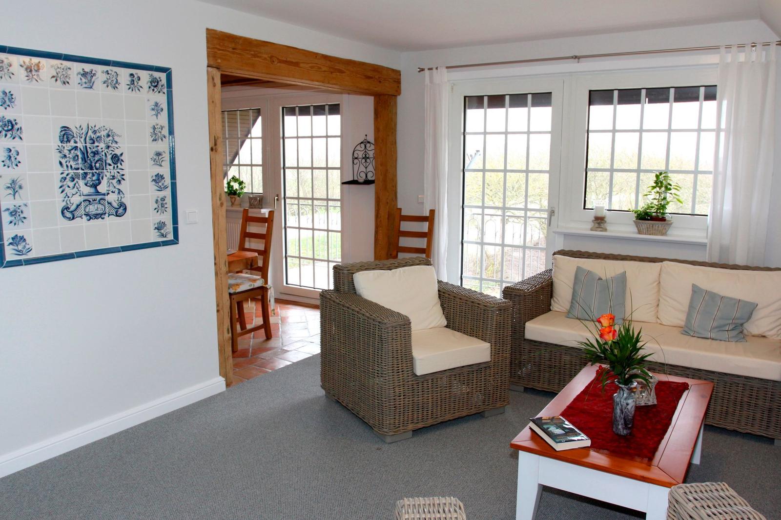 Wohnzimmer mit Rattanmöbeln, Fenstern und Wandfliesen.