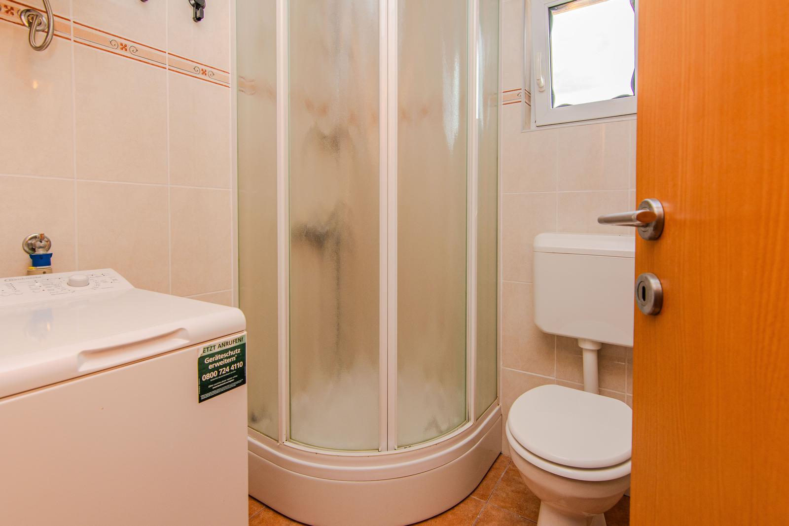 Badezimmer mit Dusche, Toilette und Waschmaschine
