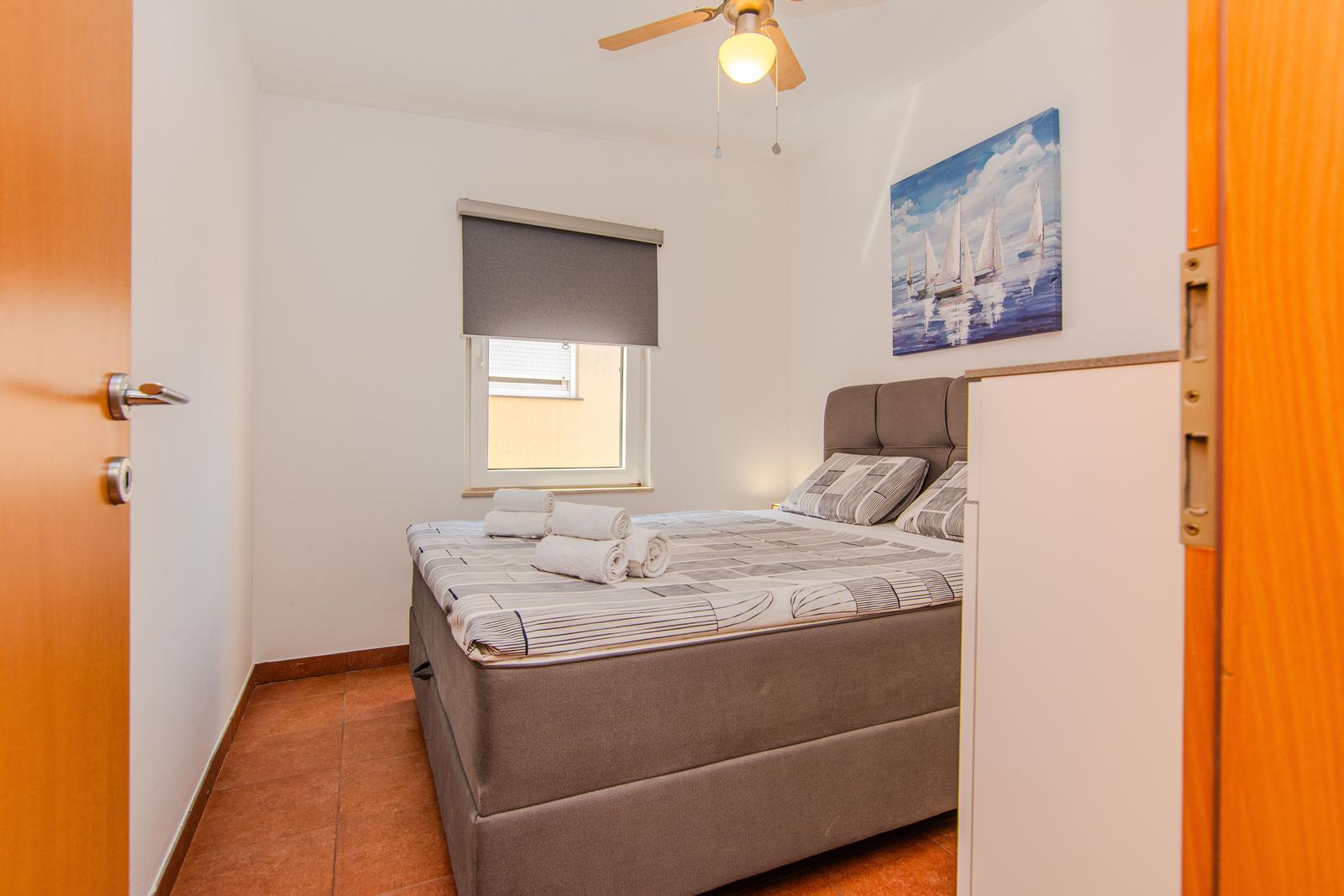 Schlafzimmer mit Bett, Fenster und Wandbild.