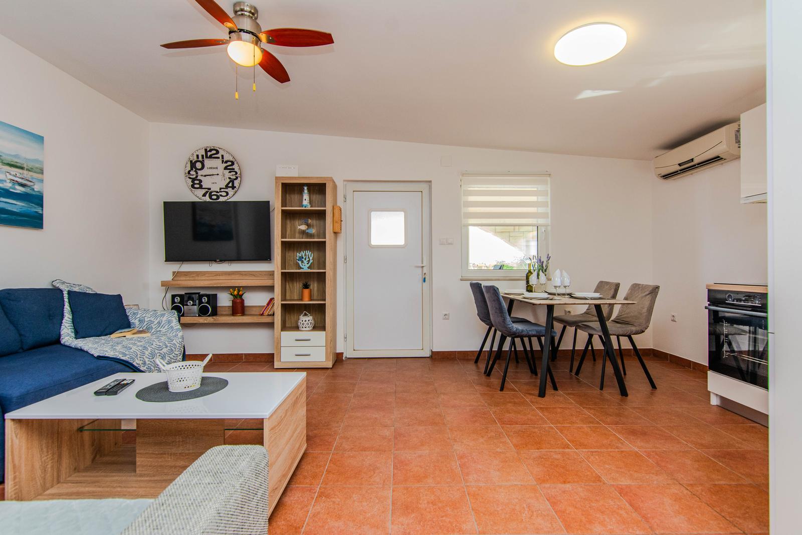 Wohn- und Essbereich mit Sofa, Tisch, Stühlen und Küchenzeile.