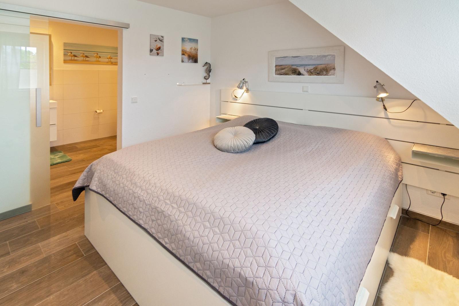 Schlafzimmer mit Doppelbett, Schlafcouch und Bad im Hintergrund.