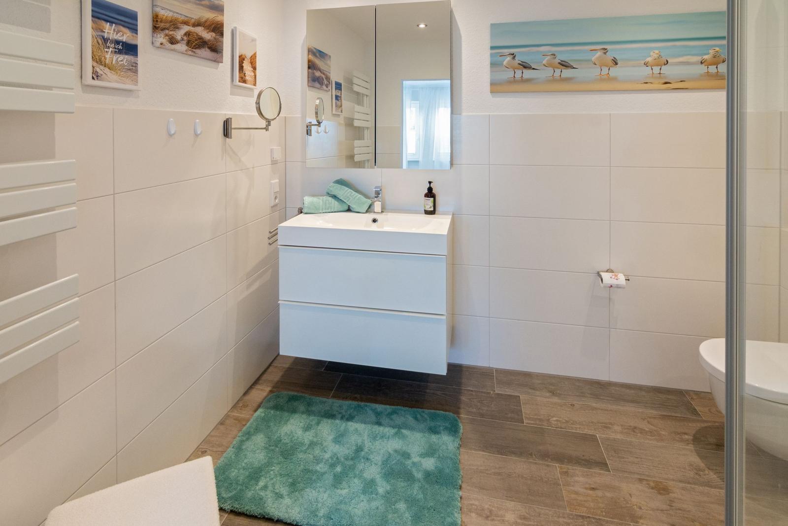 Badezimmer mit Waschbecken, Spiegel, Dusche und Teppich