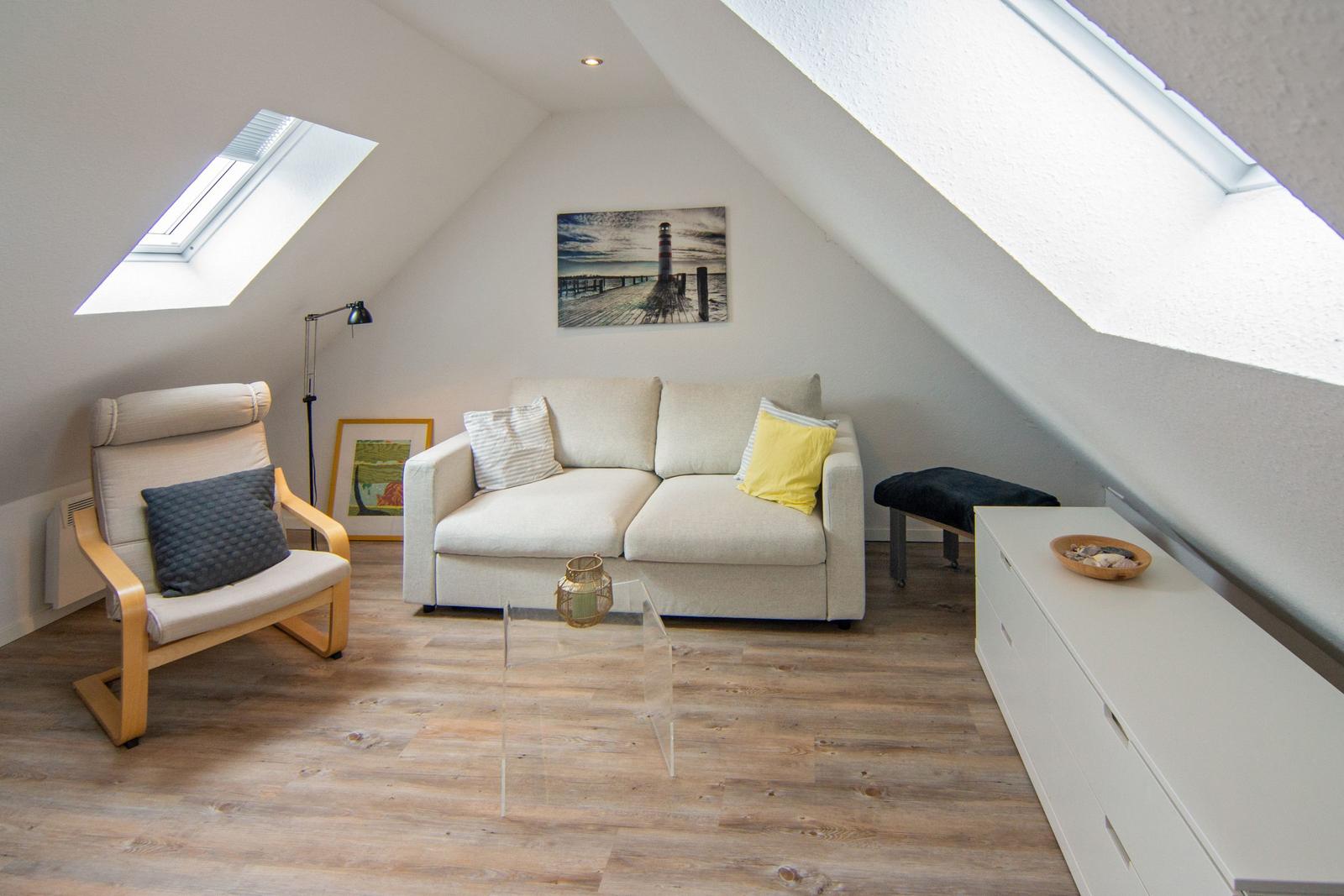 Wohnzimmer mit Sofa, Sessel, Couchtisch und Fenstern