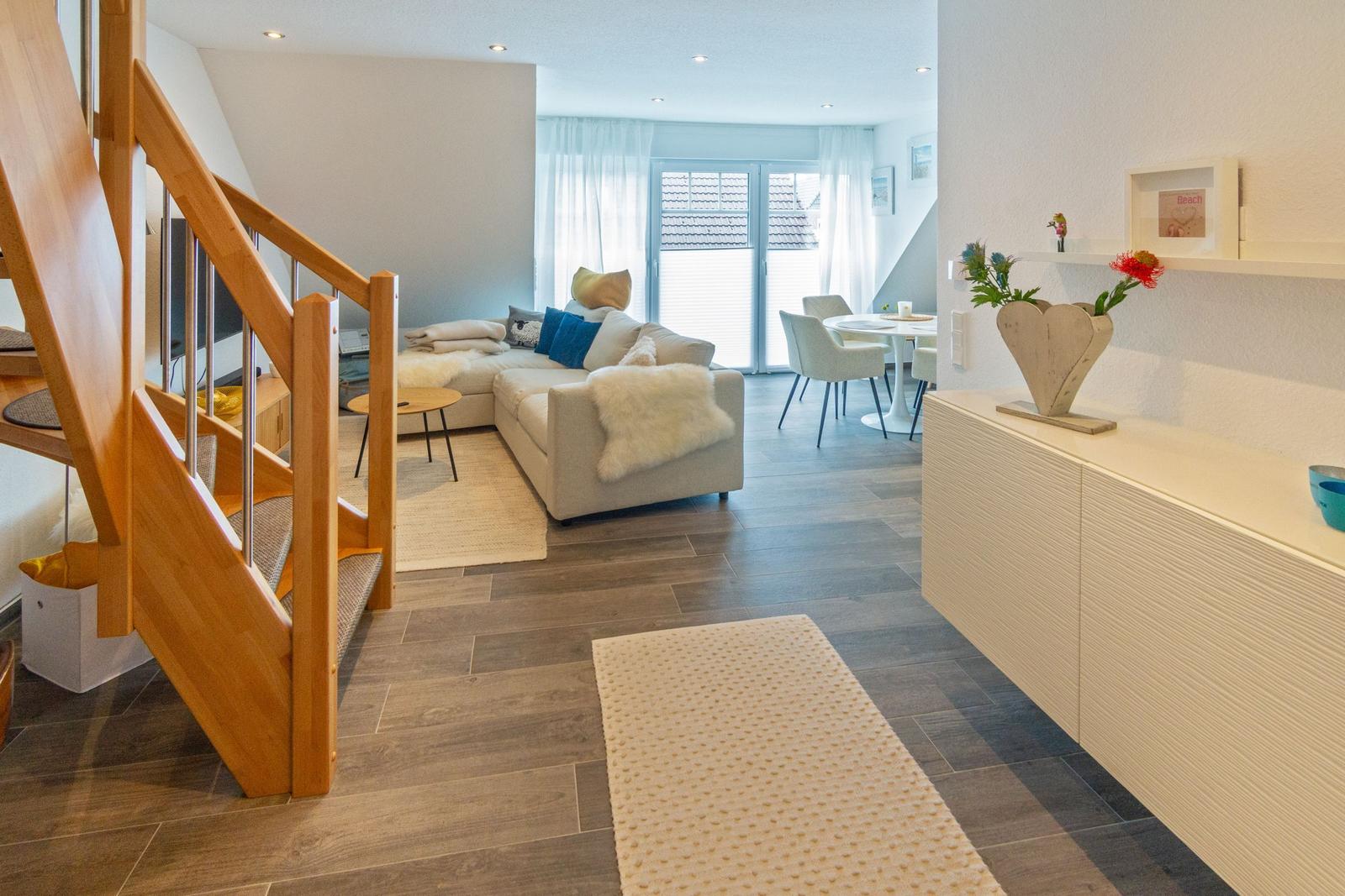 Wohn- und Essbereich mit Sofa, Tisch und Holztreppe