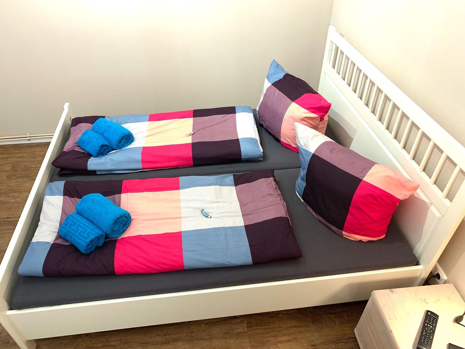 Zwei Betten mit bunten Bettwäsche und blauen Handtüchern.