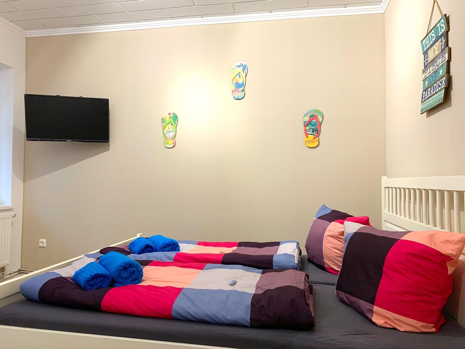 Zimmer mit zwei Betten, Wand-TV und Wanddekoration.