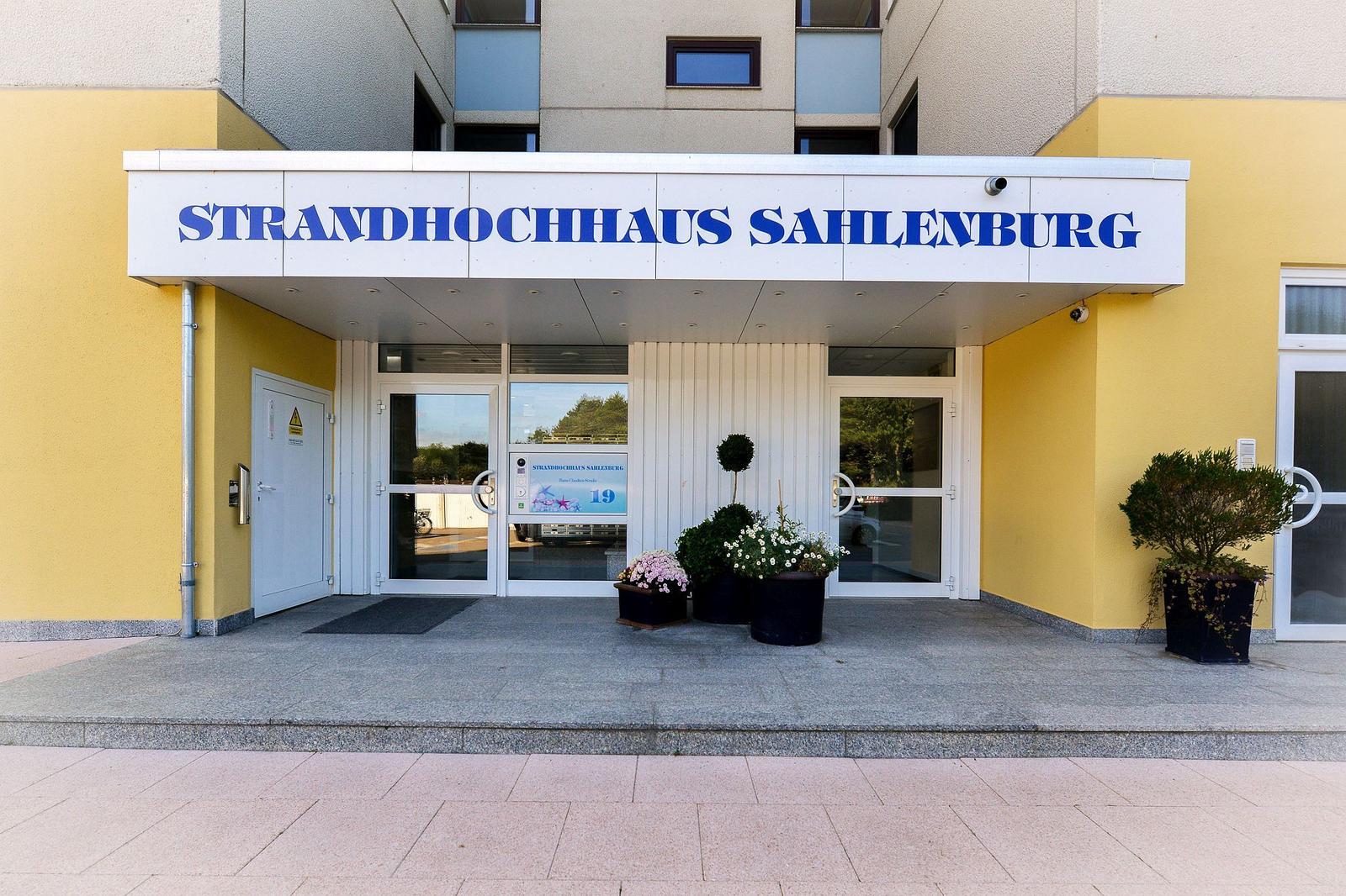 Eingangsbereich des Strandhochhauses Sahlenburg mit gelben Wänden und Pflanzen.