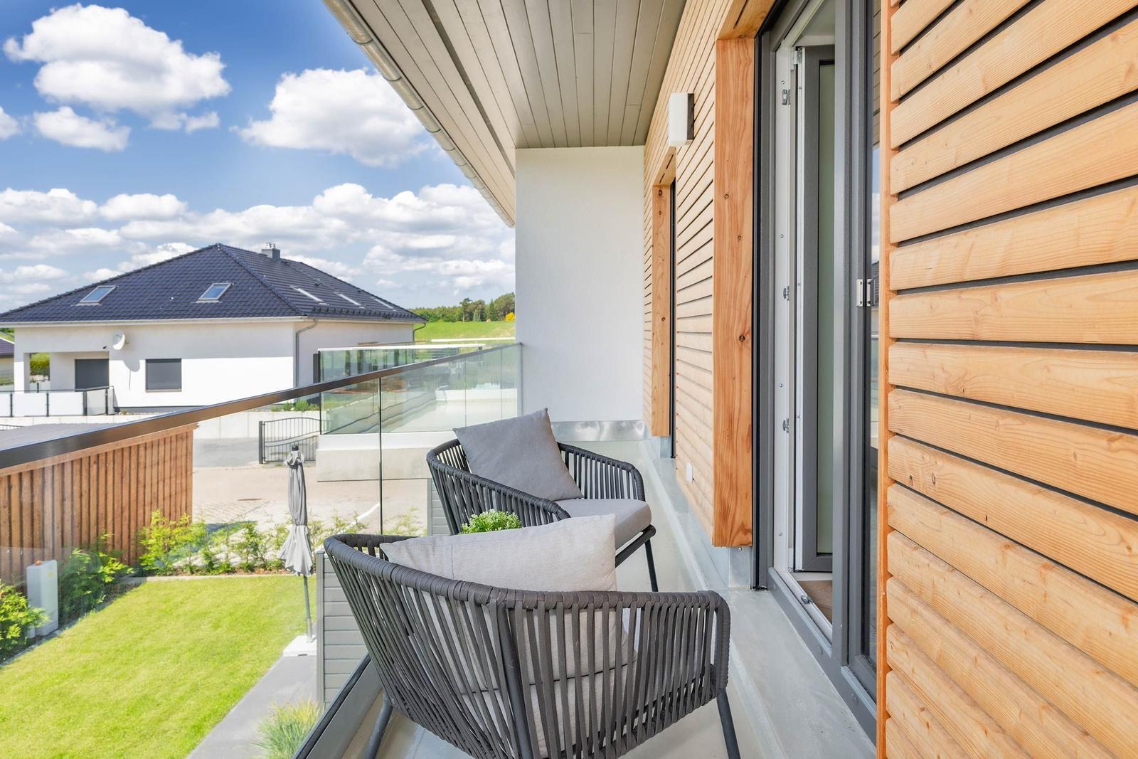 Terrasse mit zwei Sesseln und Blick auf Garten und Nachbarhaus.