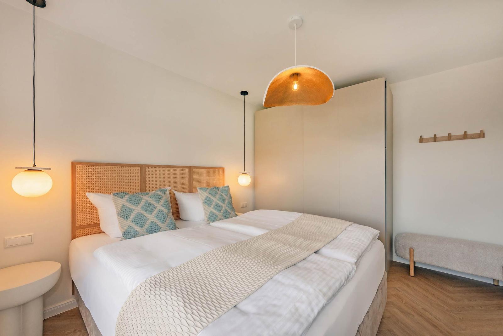 Schlafzimmer mit Bett, Nachttischen und Hängelampen.