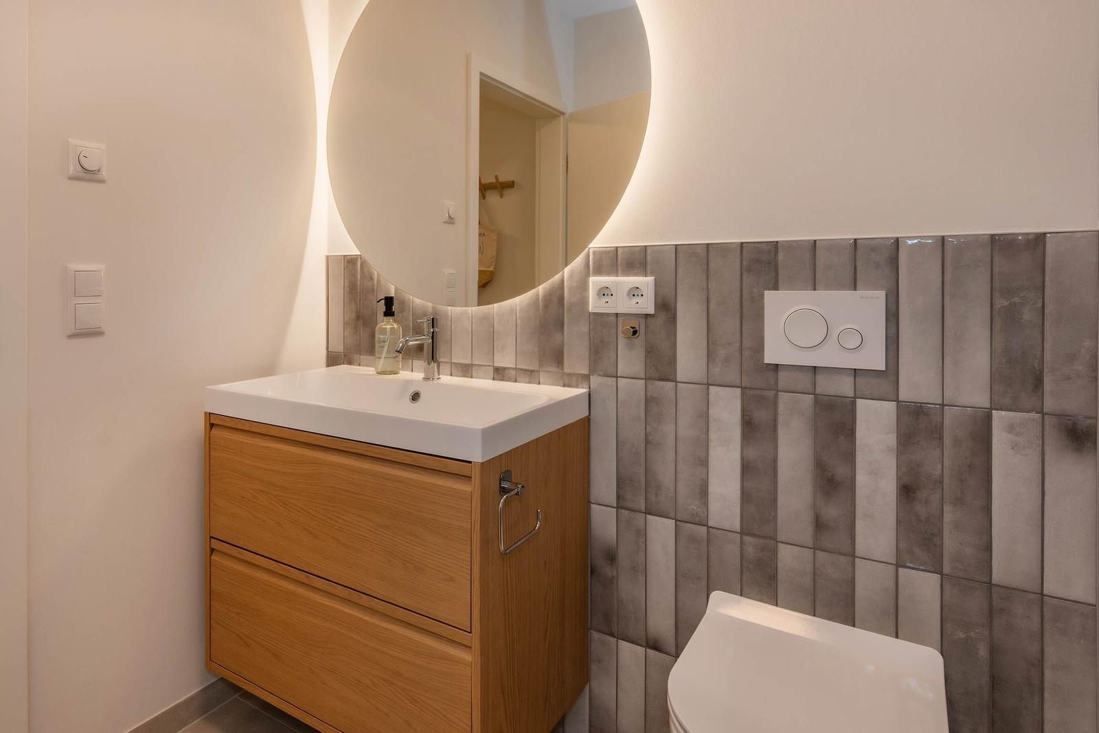 Badezimmer mit Waschbecken, Spiegel und Toilette