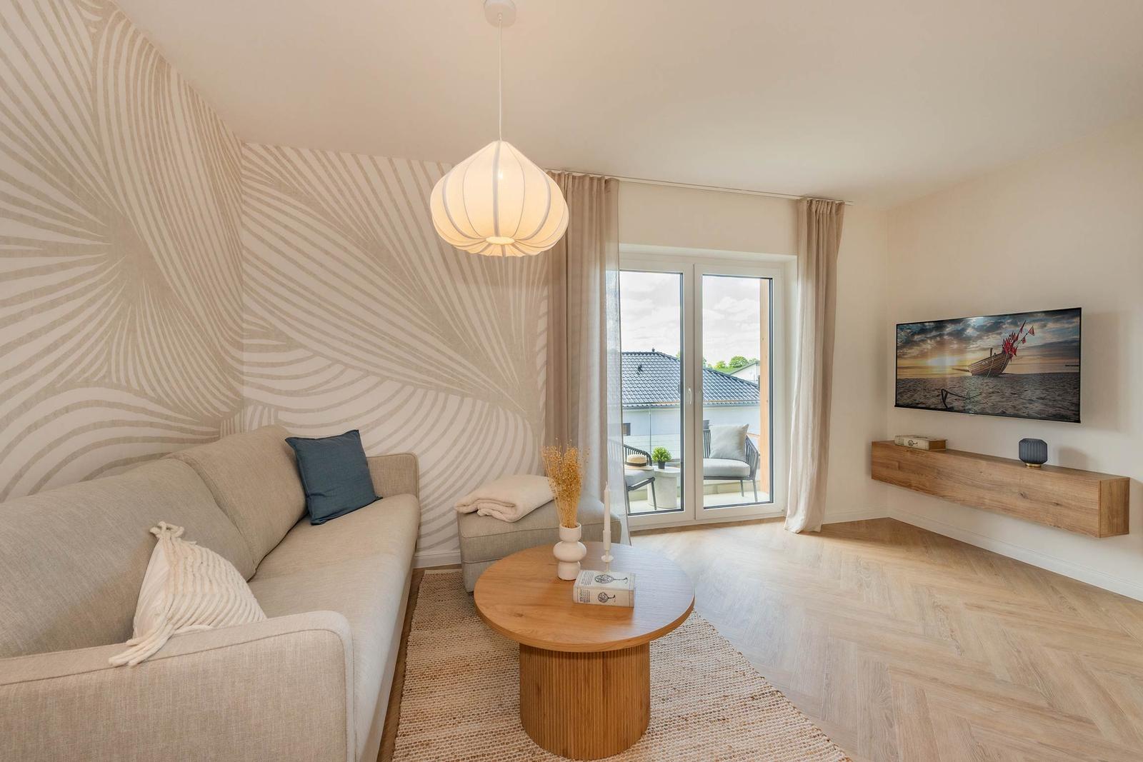 Wohnzimmer mit Sofa, TV und Balkonansicht.