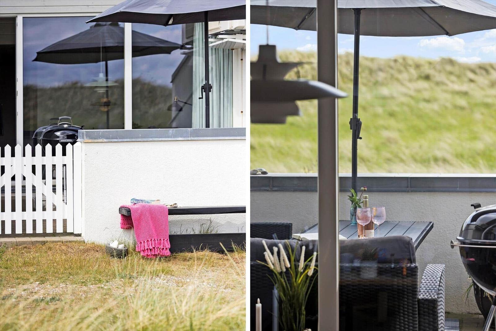 Terrace with table, chairs, and umbrella. Grill and view of grassland.