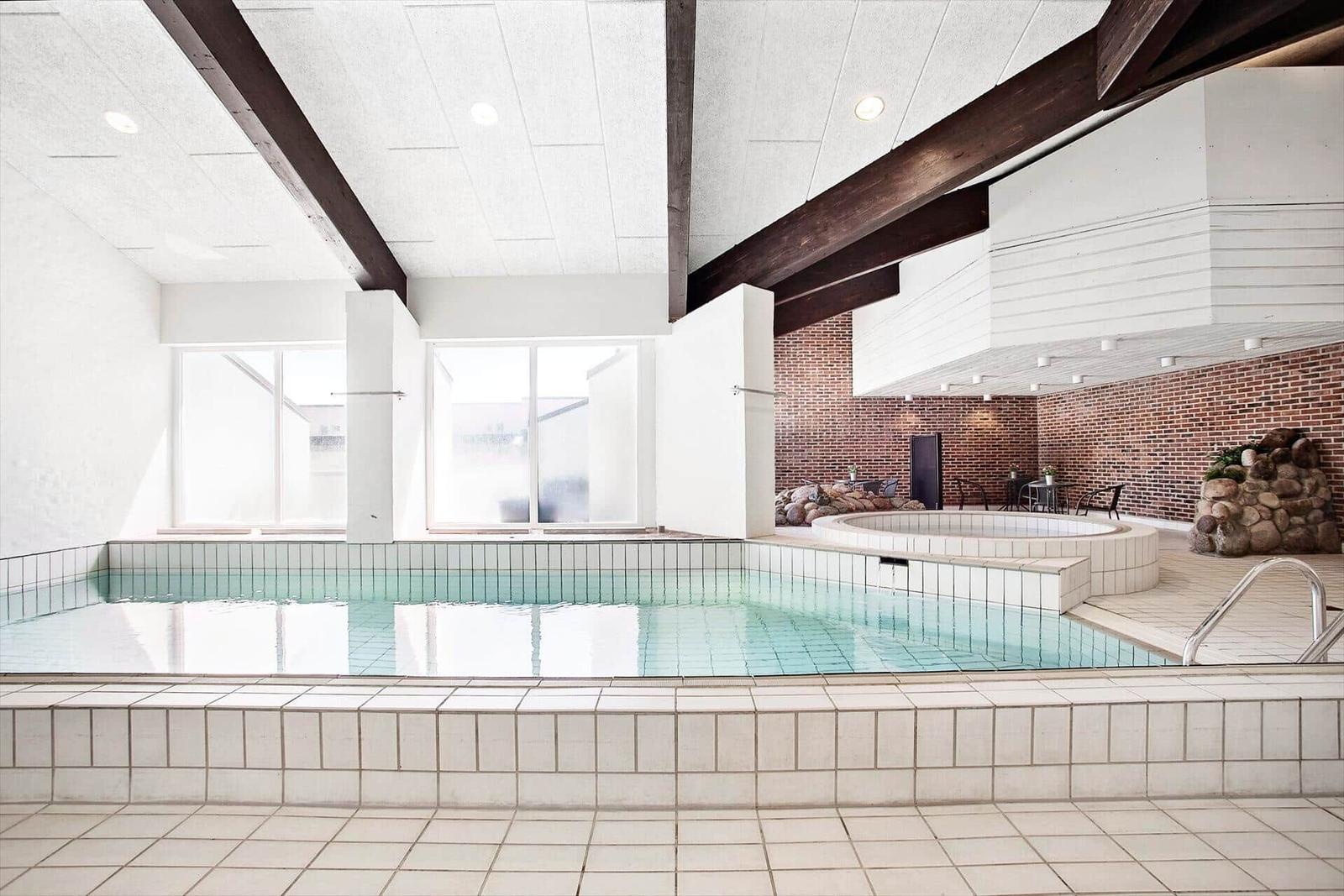 Indoor pool with hot tub and stone wall