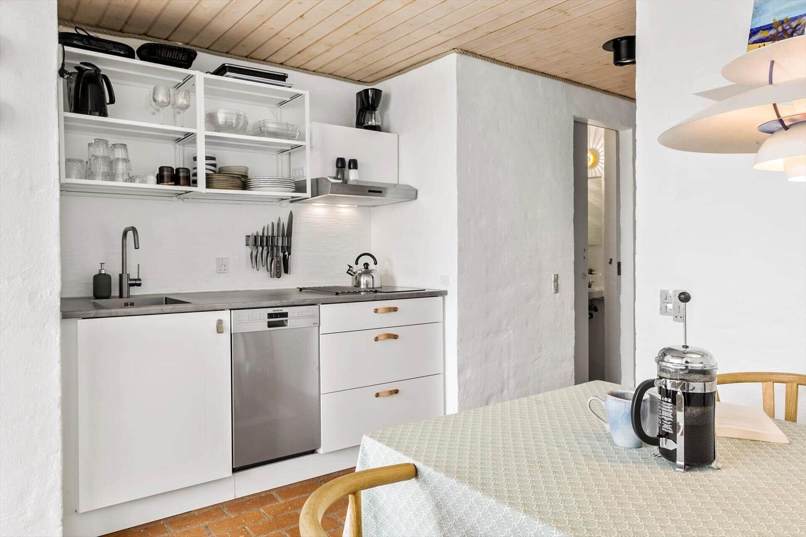 Kitchen with white cabinets, stainless steel sink, and table with chairs.