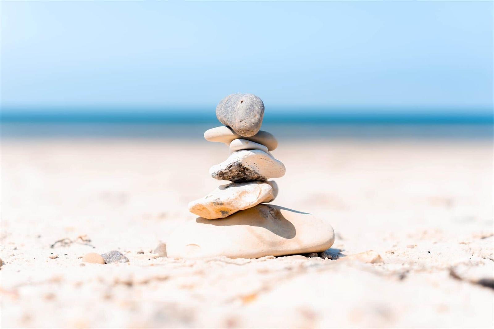Stones are balanced on the beach forming a pyramid.