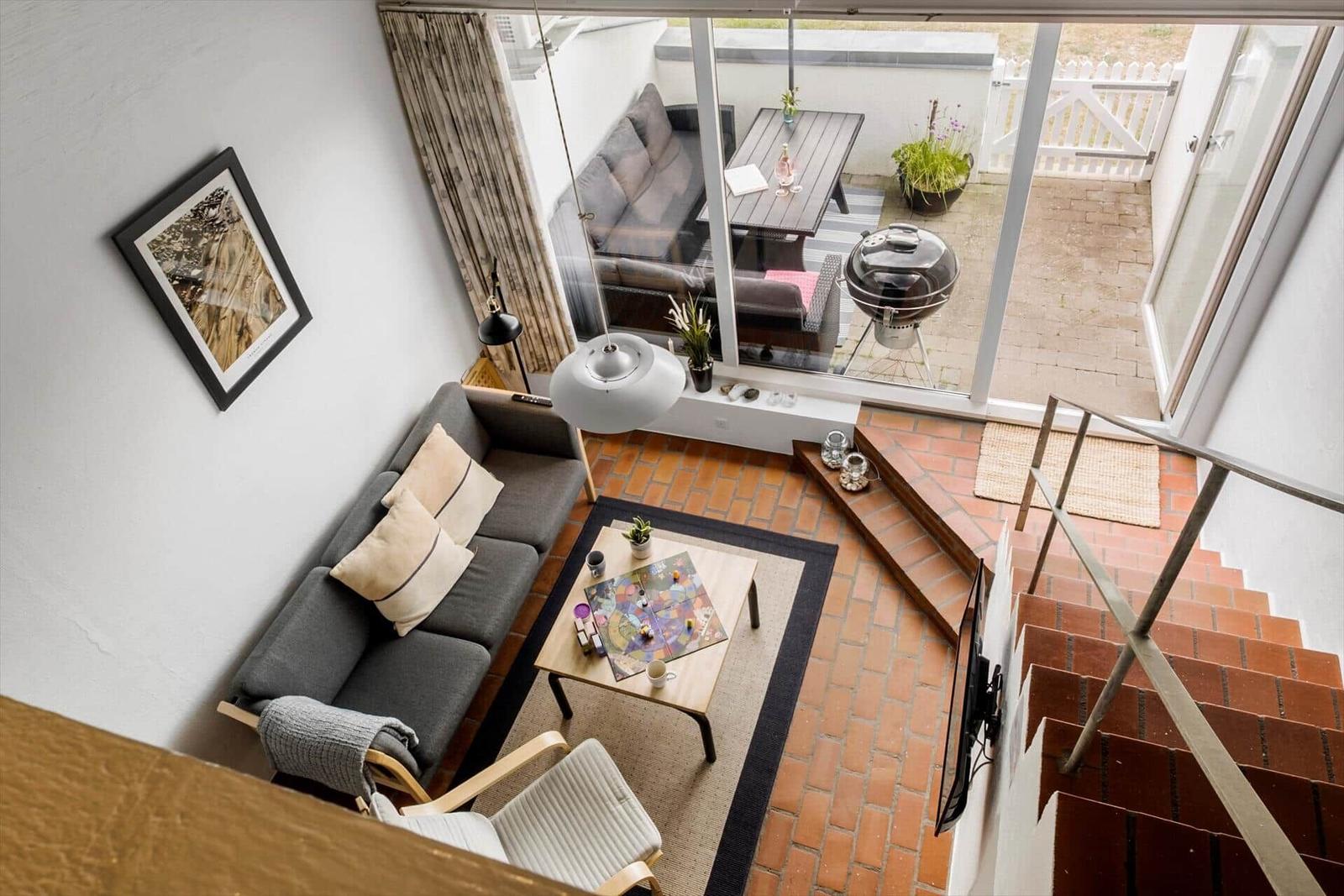 Living area with sofa, table, and terrace with grill.